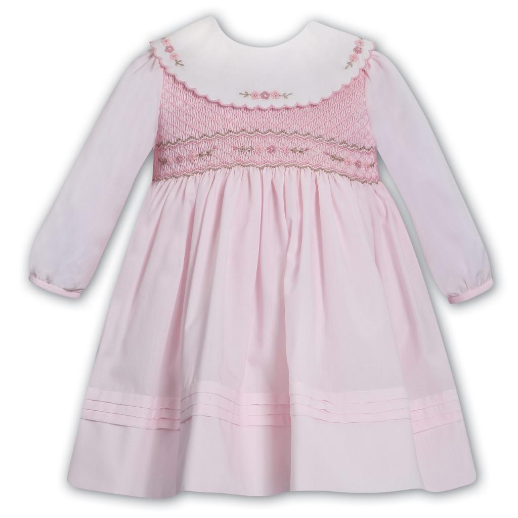 Pink baby dress with smocked details on a white background