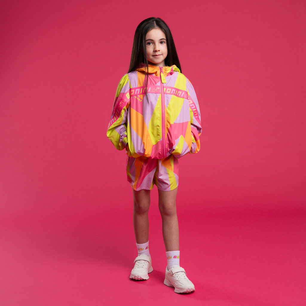 Young girl wearing a colorful outfit on a pink background