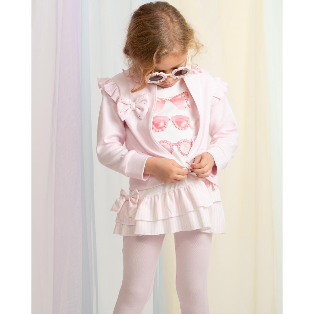 Model wearing a Caramelo pink zip‑up cardigan with ruffled shoulders, bow detail and light sparkle