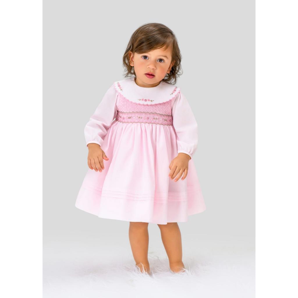 Pink baby dress with smocked details on a white background