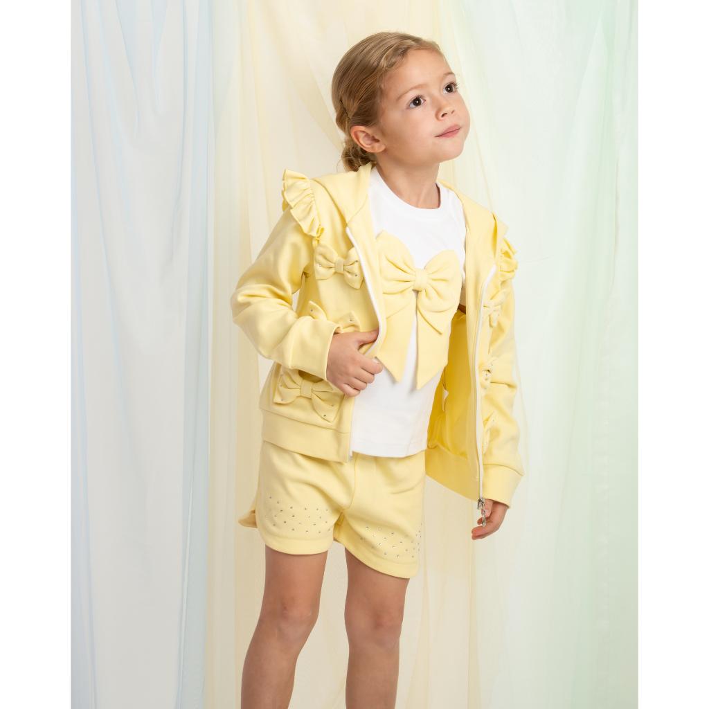 Caramelo yellow three‑piece short set for girls, featuring a bow T‑shirt, matching shorts and a ruffle‑trim jacket
