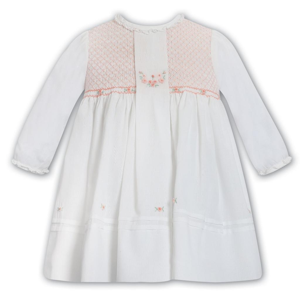 White baby dress with pink smocked bodice on a white background